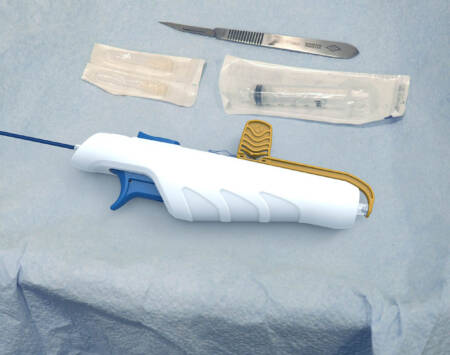 A medical device on a blue sheet, with a scalpel and syringe next to it.