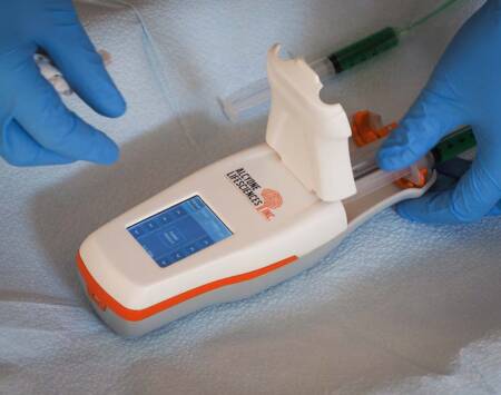 A photograph showing a syringe being loaded into an Alcyone Lifesciences device.